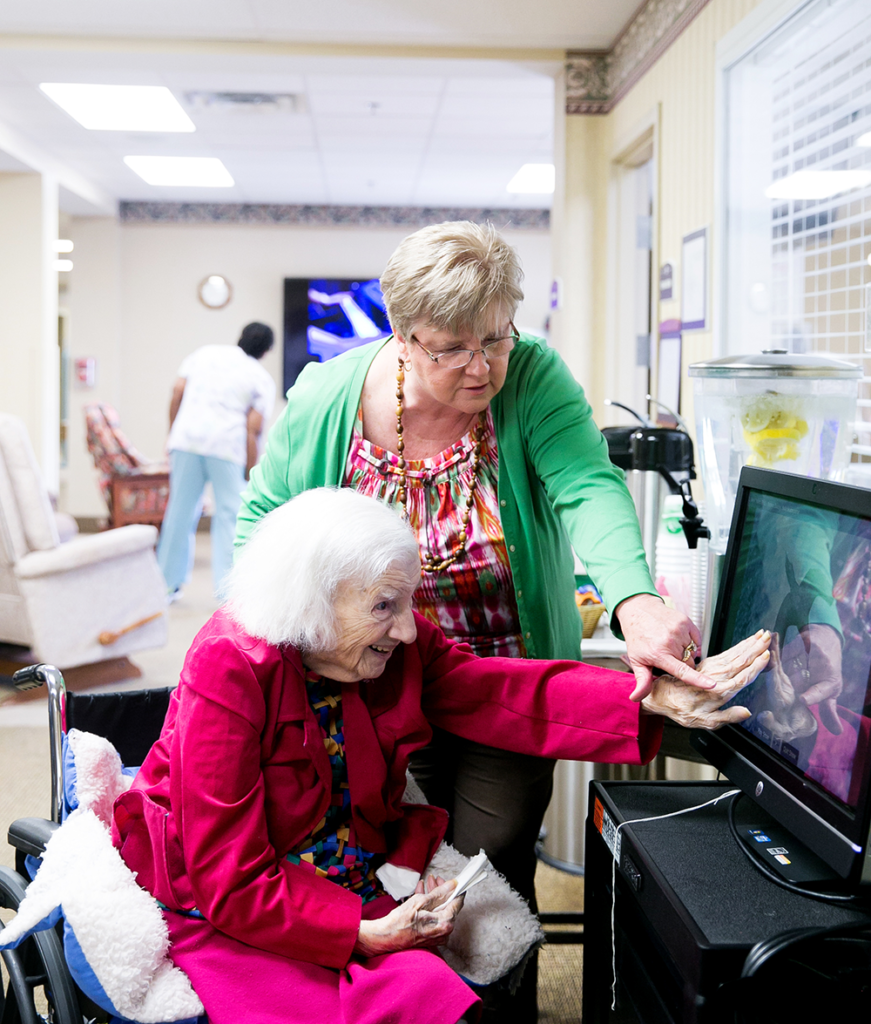 Nurse assists resident with touch screen