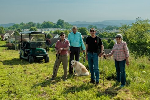 4 people and dog on hiking trail with mountain view