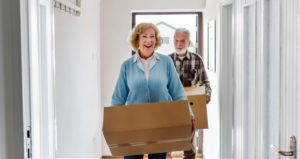 Senior couple moving boxes entering into new home