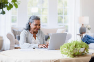 Senior woman sits at her computer answering emails to her friends